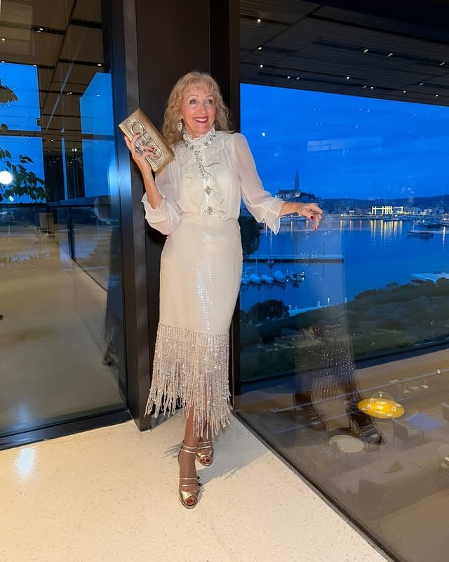 Would you wear this kind of elegance for a sunset evening? 🤍✨There’s something magical about a perfectly tailored set, soft light, and a moment that feels timeless.This stunning midi skirt with fringes and subtle sparkle, paired with a silk blouse embellished with crystals from @richradiqs , is pure quiet luxury at its finest 🤍✨I wore this look at the Grand Park Hotel Rovinj, right by the glass wall as the sun was setting and the blue hour wrapped the old town of Rovinj in its glow.The quality, the movement, the details — no wonder so many elegant ladies stopped me to ask where it’s from.This luxurious set is by @richradiqs in the color of the Year 2026 Cloud Dancer — refined, feminine, and designed for women who love timeless elegance.✨ Shop the look via the link Rich Radi Q’s in my BIO (open links)💫 Use my exclusive 20% OFF code before checkout: LILIJANAKASTELIDetails:• Skirt: C8A4345 – SKIRT – APRICOT• Blouse: G9E771 – BLOUSE – CREAMY WHITE• Sandals: @casadeiofficial • Clutch: @jimmychoo Hotel: @maistra_collection Because elegance isn’t about trends — it’s about how you feel when you wear something truly special 🤍✨Please tell me below:✨ Are you more minimal elegance or sparkle & statement?📌 Save this post for evening outfit inspiration💌 Send it to a friend who loves luxury style➕ Follow me for elegant fashion, confidence & lifestyle inspirationProducts gifted by @richradiqs 🤍✨Other pieces are my own.#gifted ............#richradiqs #richradiqsdress